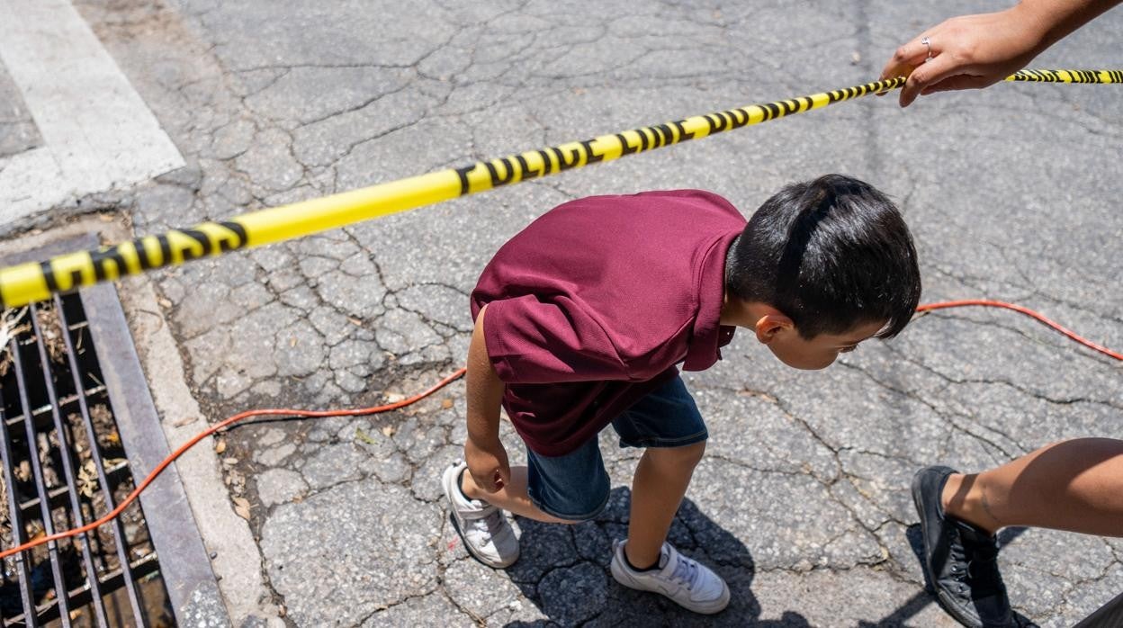 Un niño pasa bajo una cinta policial junto a la escuela elemental Robb