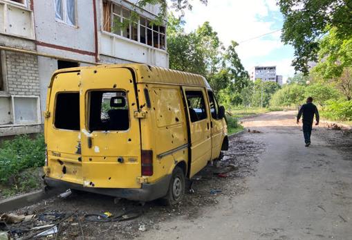 Un hombre camina junto a una furgoneta agujereada por la metralla