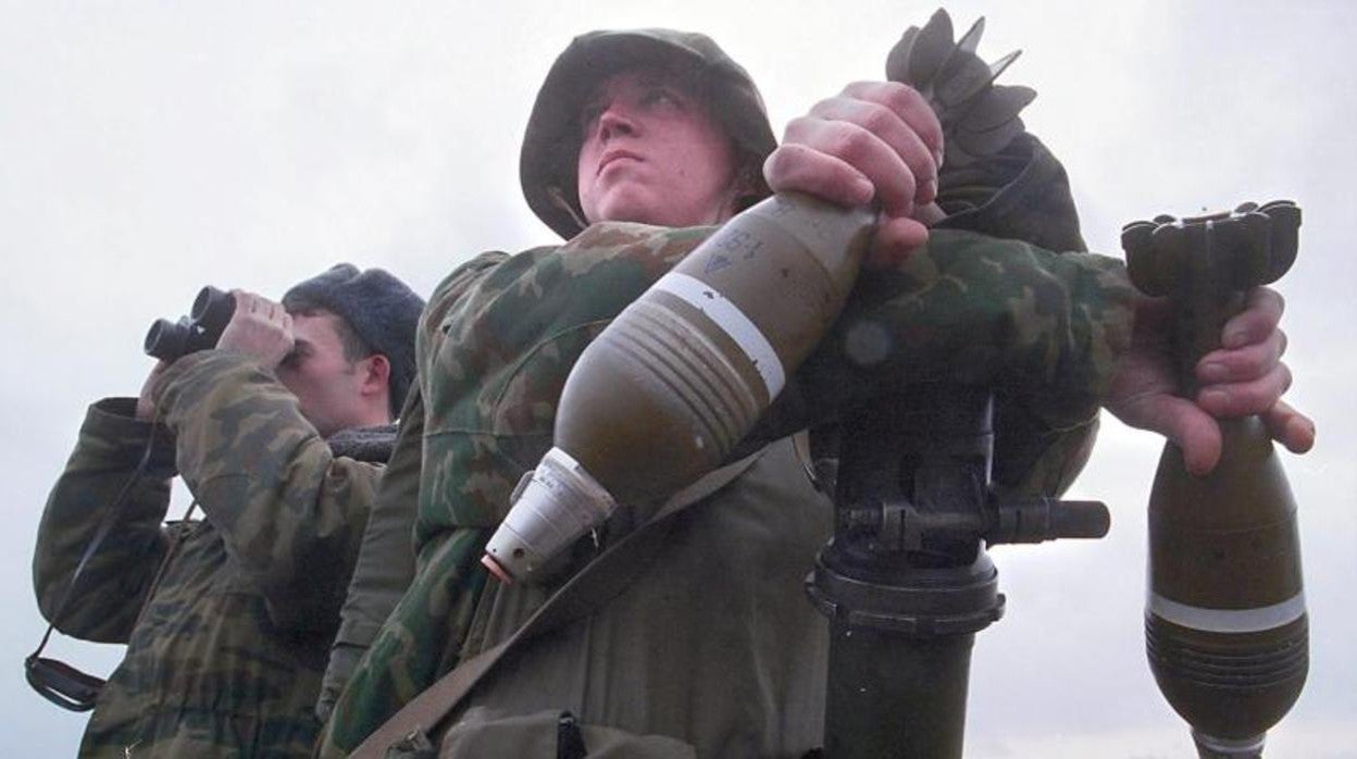 Un soldado ruso sostiene granadas mientras un oficial vigila las posiciones de las tropas rebeldes al sur de Chechenia, en febrero de 2000