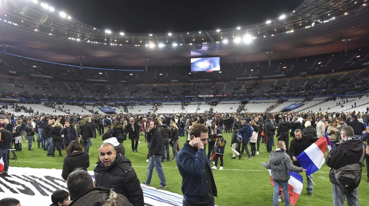 Los espectadores que asistían al encuentro amistoso de fútbol entre Francia Alemania se concentran en el césped del Stade de France tras las explosiones que sacudieron las inmediaciones del estadio, en París (Francia), 13 de noviembre de 2015