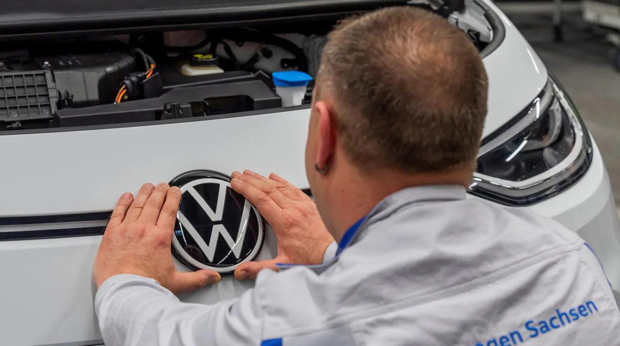 Un empleado de Volkswagen coloca un emblema en uno de los vehículos de la compañía