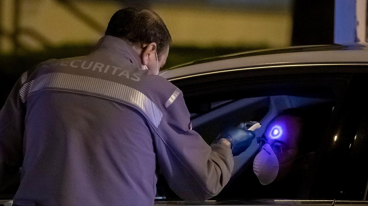 Un guardia de seguridad toma la temperatura a un conductor en el control de entrada de los trabajadores del primer turno de la factoría de Renault de Sevilla