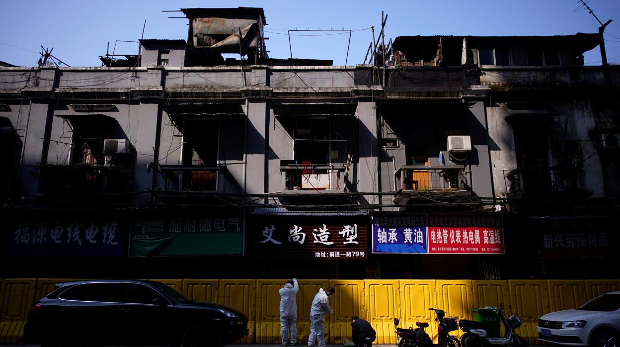 Empleados retiran vallas de protección en una calle de Wuhan, China