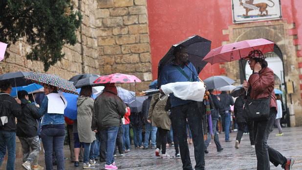 Turistas con paraguas en la entrada del Alcázar