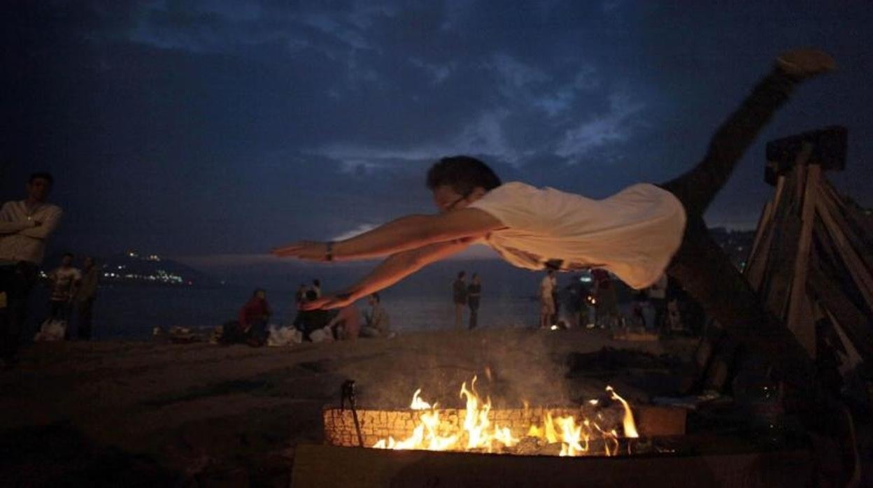 Un joven salta una pequeña hoguera en la playa del Orzán, en A Coruña, durante la celebración de San Juan