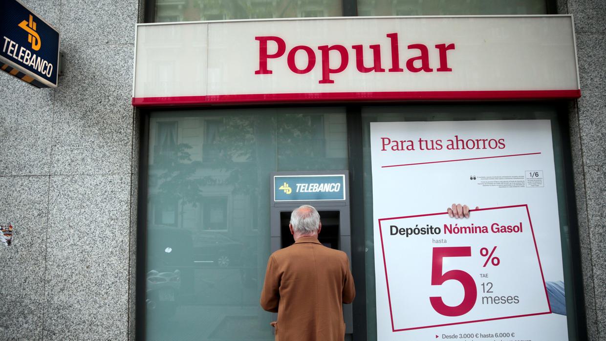 Un hombre utiliza el cajero automática en una oficina del Banco Popular