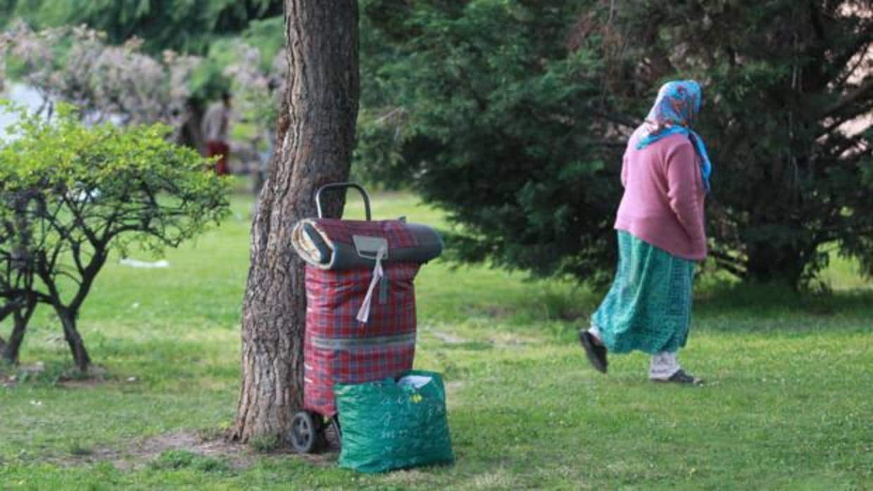 Una mujer rumana espera con sus pertenencias en un parque