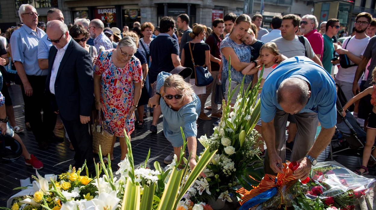 Un grupo de personas deposita flores en Las Ramblas en memoria de las víctimas del 17-A