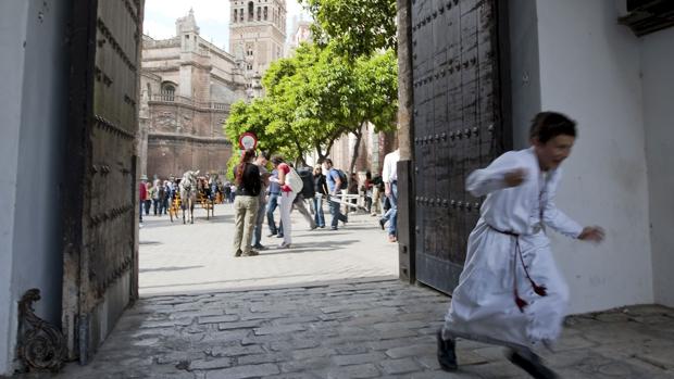 Un joven nazareno de la Hermandad del Cerro juega junto a la Giralda y la Catedral de Sevilla