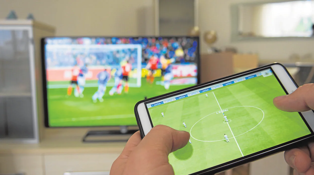 Un usuario sintoniza un partido de fútbol en la televisión mientras ve un vídeo en su teléfono móvil