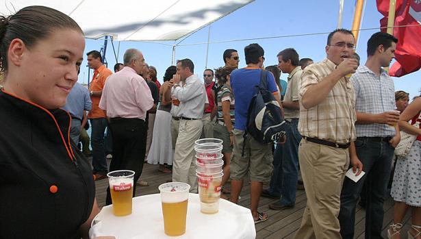 Una camarera sirve cervezas a bordo de un velero participante en la escala anterior de la Gran Regata en Cádiz