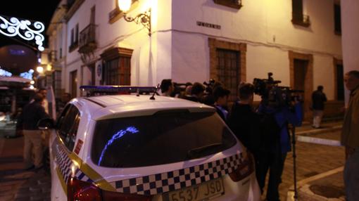 Vecinos y medios apostados junto a coche de la Policía Local