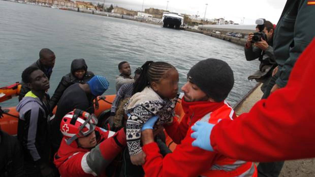 Cruz Roja ayuda a bajar a una niña de la lancha en el puerto de Tarifa (