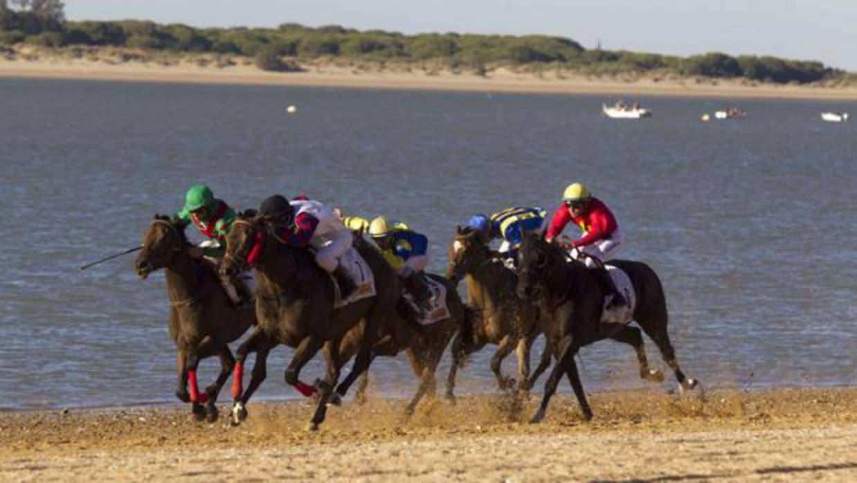 Imagen de archivo de las carreras de caballos en la playa de Sanlúcar con el Coto de Doñana de fondo