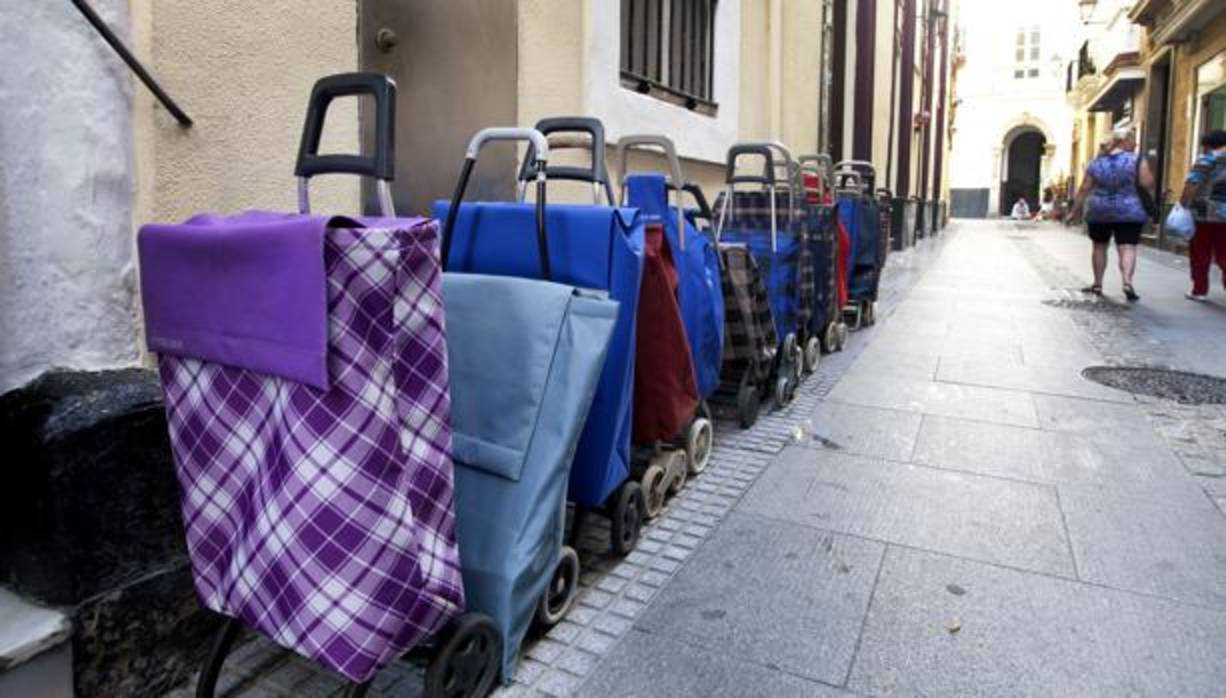 Una fila de carritos de la compra esperando delante de un comedor social en Cádiz