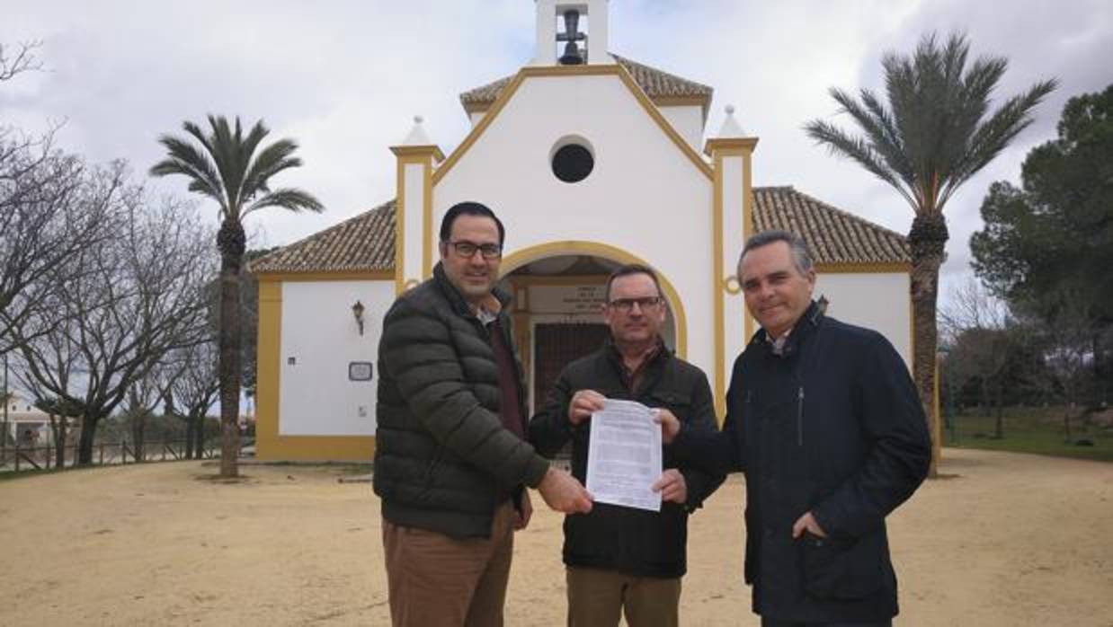 Representantes locales del PP y Juan Bueno, a la derecha, con la resolución de la comisión ante la ermita de la patrona