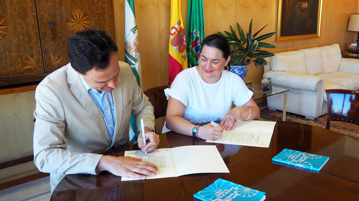 Momento en que el alcalde estampa su rúbrica en el pacto en presencia de la secretaria de Fakali