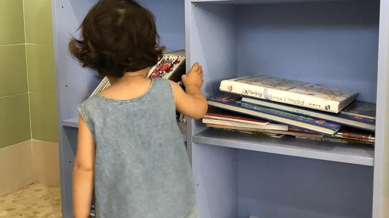 Una pequeña se interesa por los libros del punto de lectura