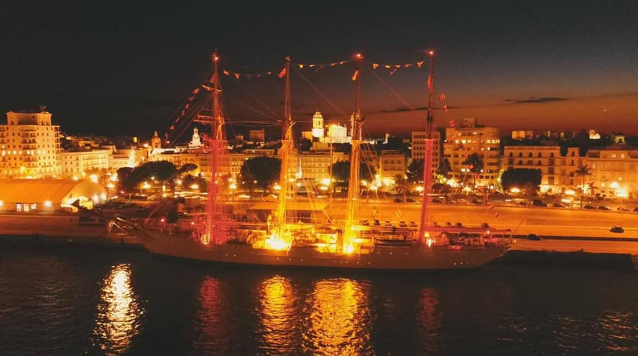 Vista aérea del Juan Sebastián de Elcano en el puerto de Cádiz iluminado con la bandera de España.