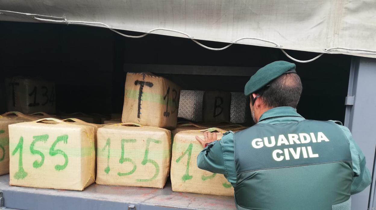 Agente de la Guardia Civil, con los fardos incautados.