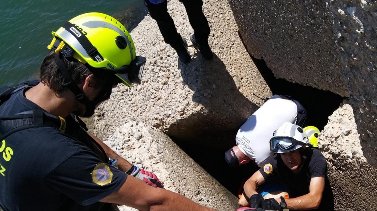 Los bomberos y Protección Civill rescatan el cuerpo del pescador.