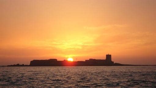 El sol se oculta tras el islote de Sancti Petri, en San Fernando