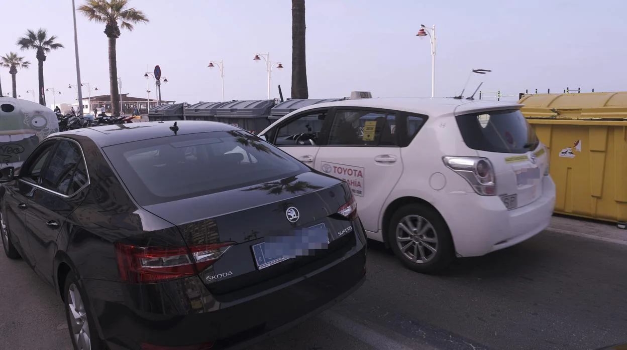 Un taxi circula junto a un Uber estacionado en el Paseo Marítimo en el estreno de la compañía en Cádiz.