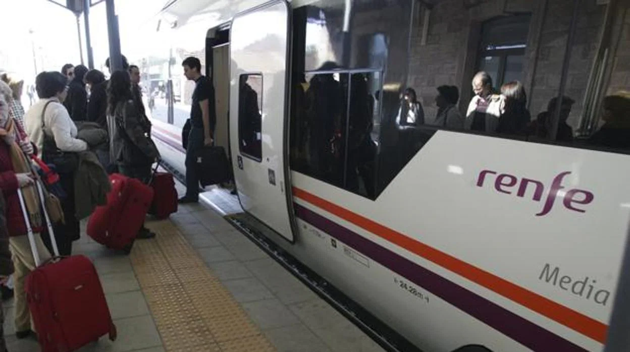 Varios pasajeros aguardan para entrar en un tren de Media Distancia