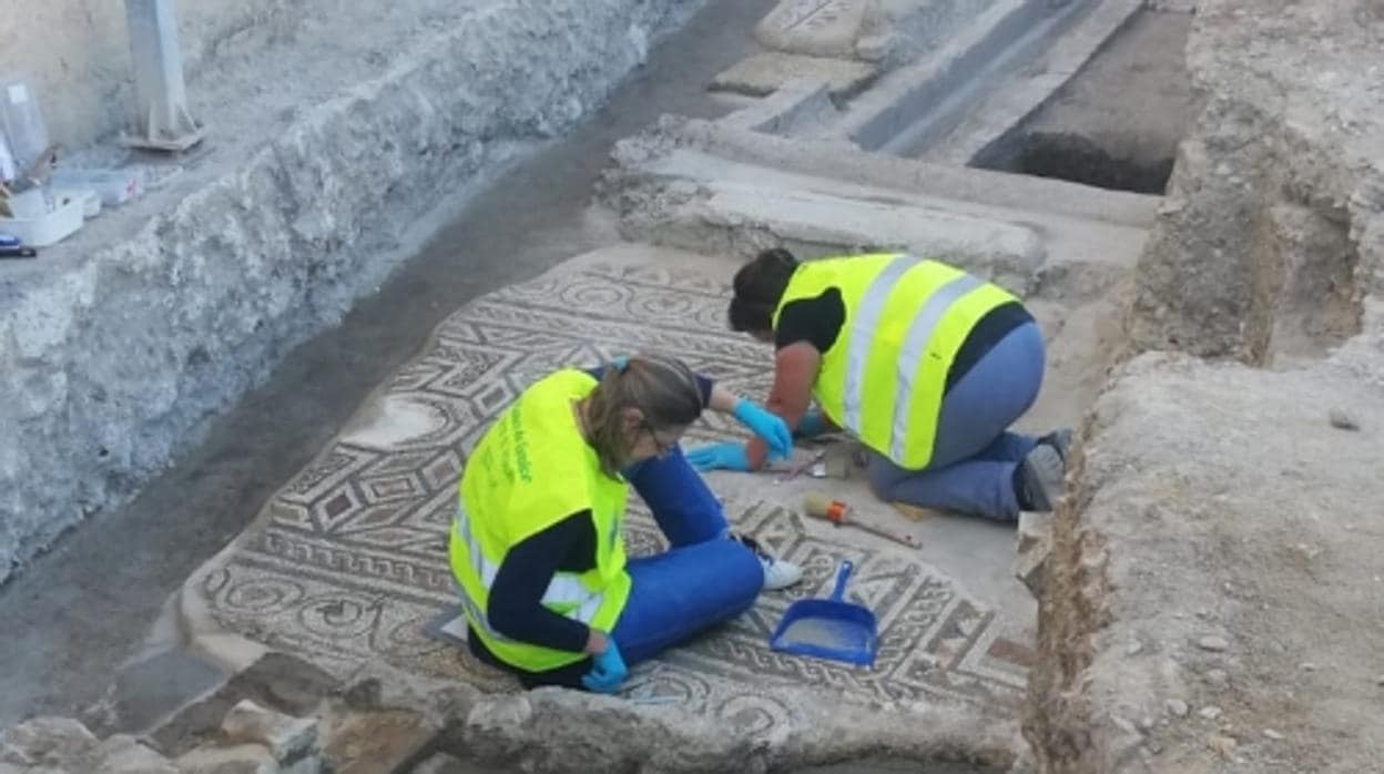 Dos personas trabajan sobre el nuevo mosaico descubierto en la domus romana del Picadero