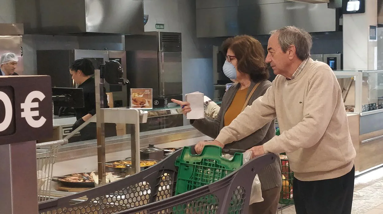 Una mujer realiza la compra en un supermercado con mascarilla.