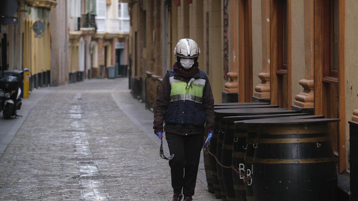 Una repartidora, protegida con mascarilla y guantes, realiza su trabajo en Cádiz.