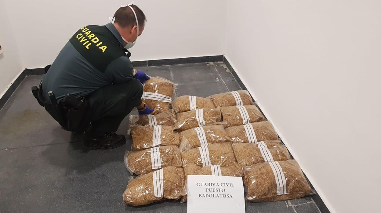 Un agente de la Guardia Civil del puesto de Badolatosa junto con el tabaco intervenido