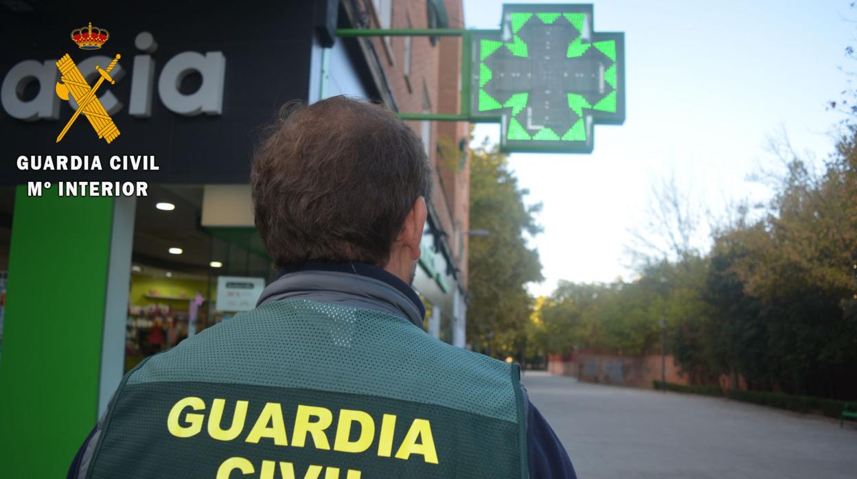 Un agente delante de una farmacia, un negocio afectado por este negocio ilícito