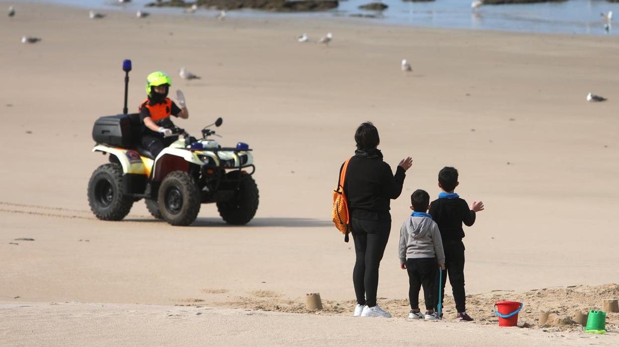 Niños jugando junto a su madre en una playa de Cádiz este domingo.