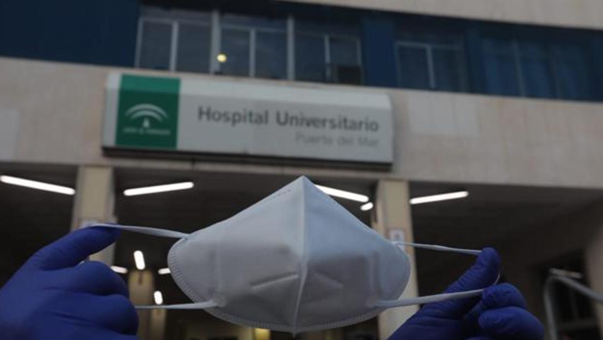 Un sanitario muestra una mascarilla frente al hospital gaditano Puerta del Mar.