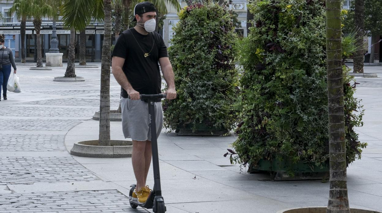 Un joven se traslada en su patinete durante la desescalada en Cádiz.