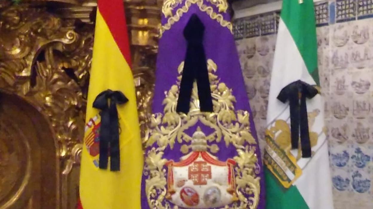 Crespones negros en el guión de la hermandad, así como en las banderas de España y Andalucía