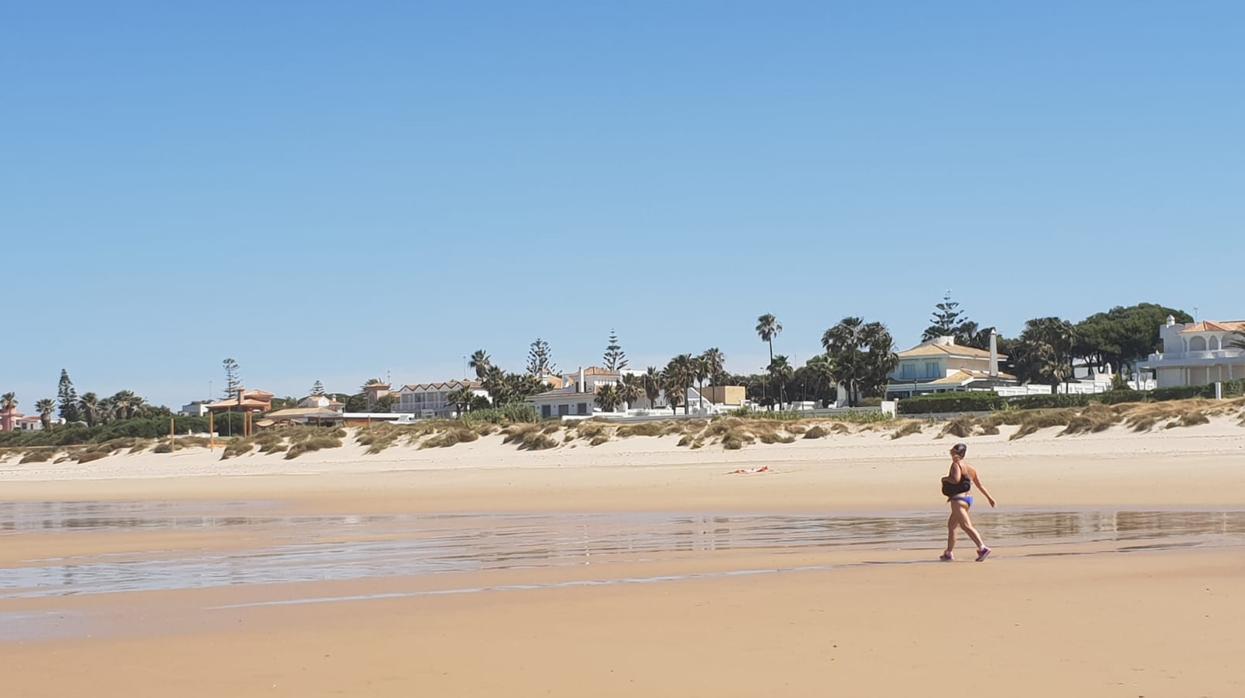 Una usuaria paseando por la playa chiclanera de la Barrosa.