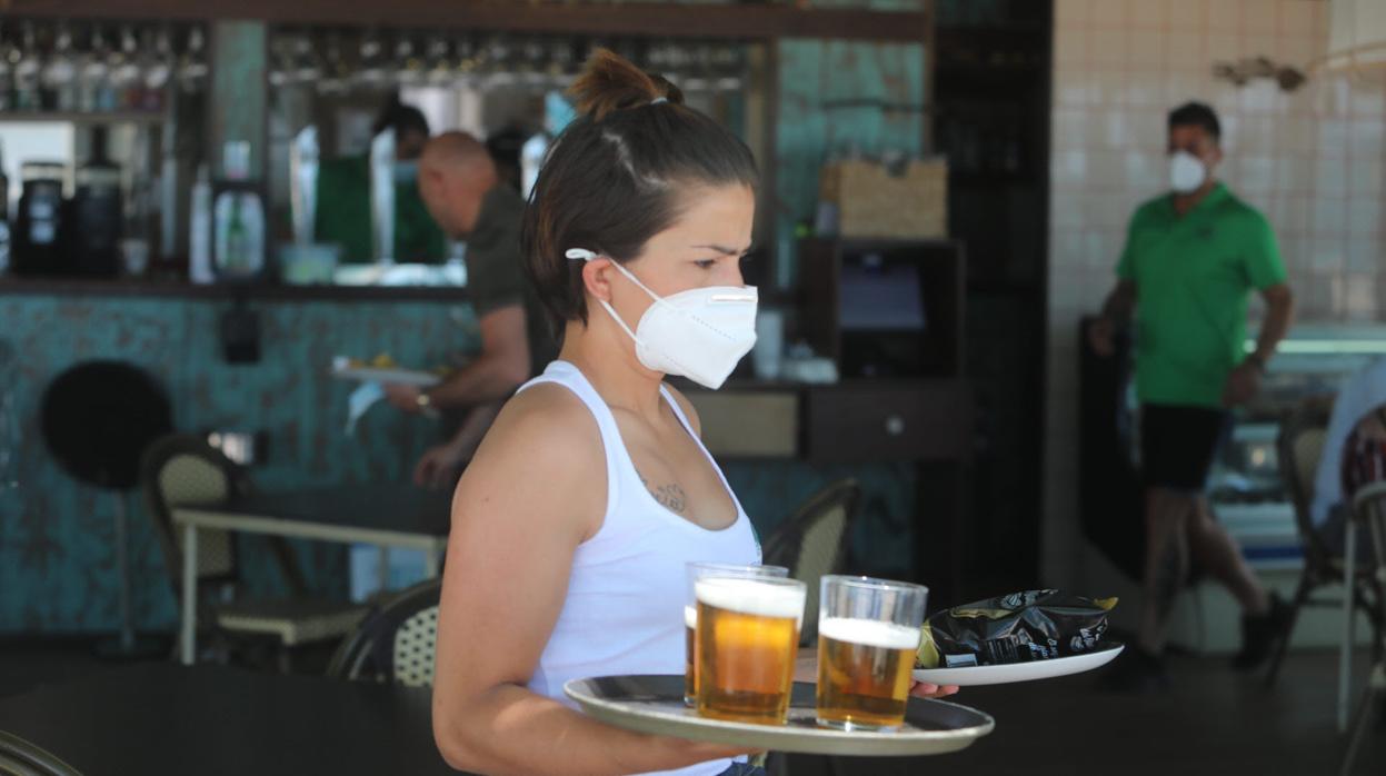 Una camarera sirve unas cervezas en un chiringuito de Cádiz.