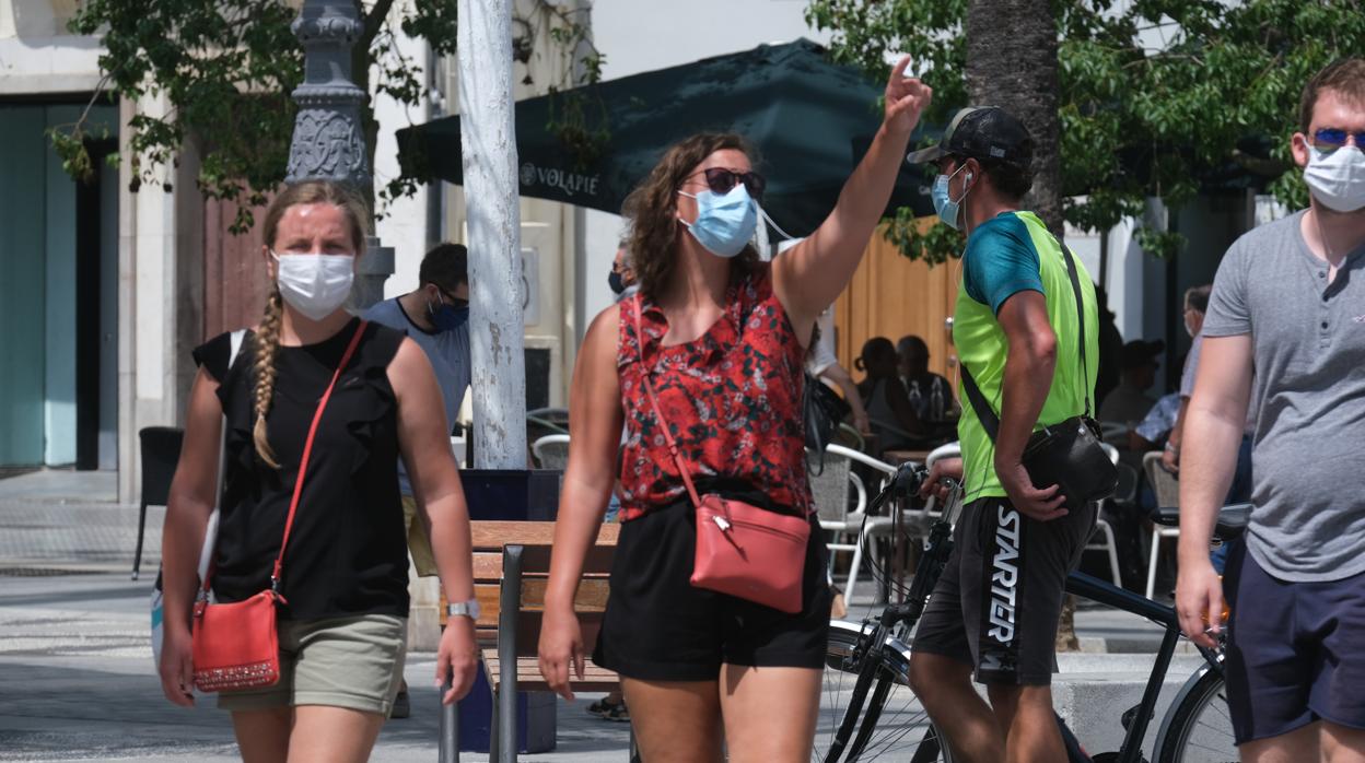 Varios jóvenes caminan con mascarilla por las calles de Cádiz capital, la tercera localidad con más casos activos.