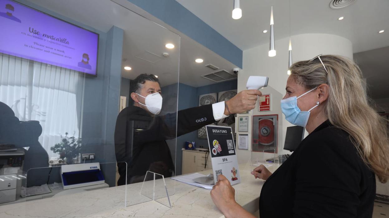 Un recepcionista toma la temperatura a una cliente en un hotel de Cádiz.