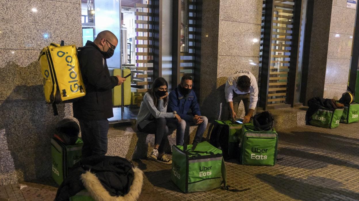 ‘Riders’ de Uber Eats y Glovo esperan pedidos a las puertas del McDonalds en Cádiz capital.