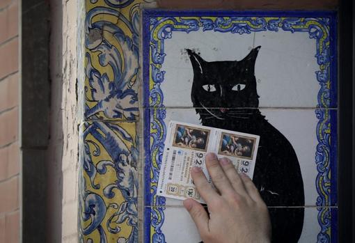 Una persona frota dos décimos sobre el azulejo del Gato negro