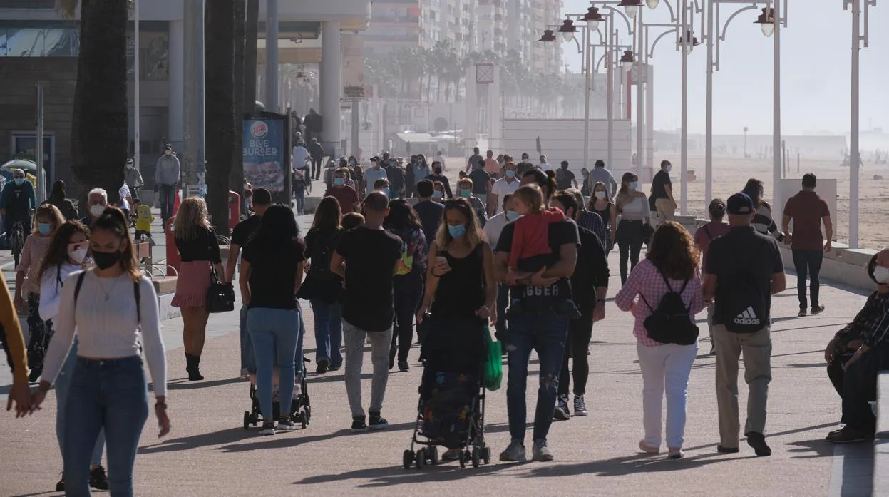 Gente con mascarillas en el Paseo Marítimo de Cádiz, este domingo.