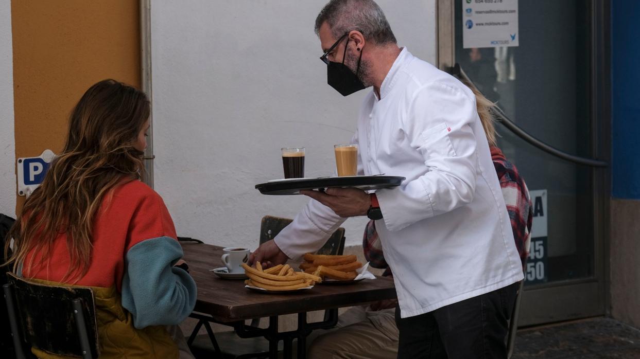 Un camarero sirve café y churros, este jueves en Cádiz.