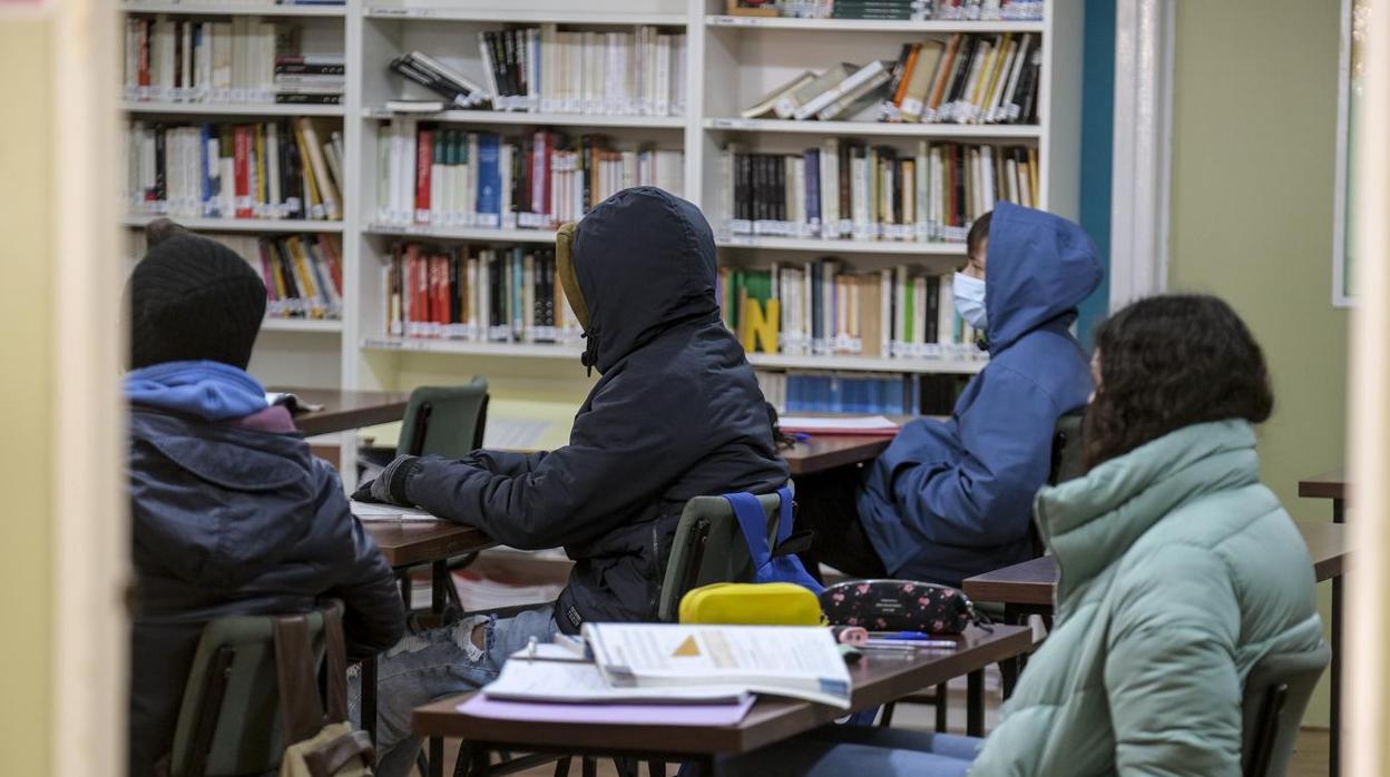 Cuatro alumnos abrigados con chaquetones en el interior de una clase