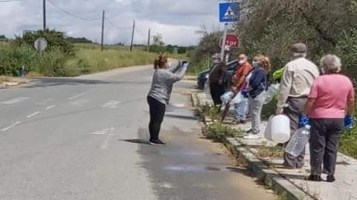 Un grupo de vecinos del Sector F de Almensilla hacen cola para recoger agua potable de un grifo