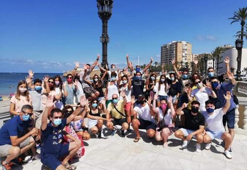 Un grupo numeroso de turistas posan durante un tour frente a La Caleta.