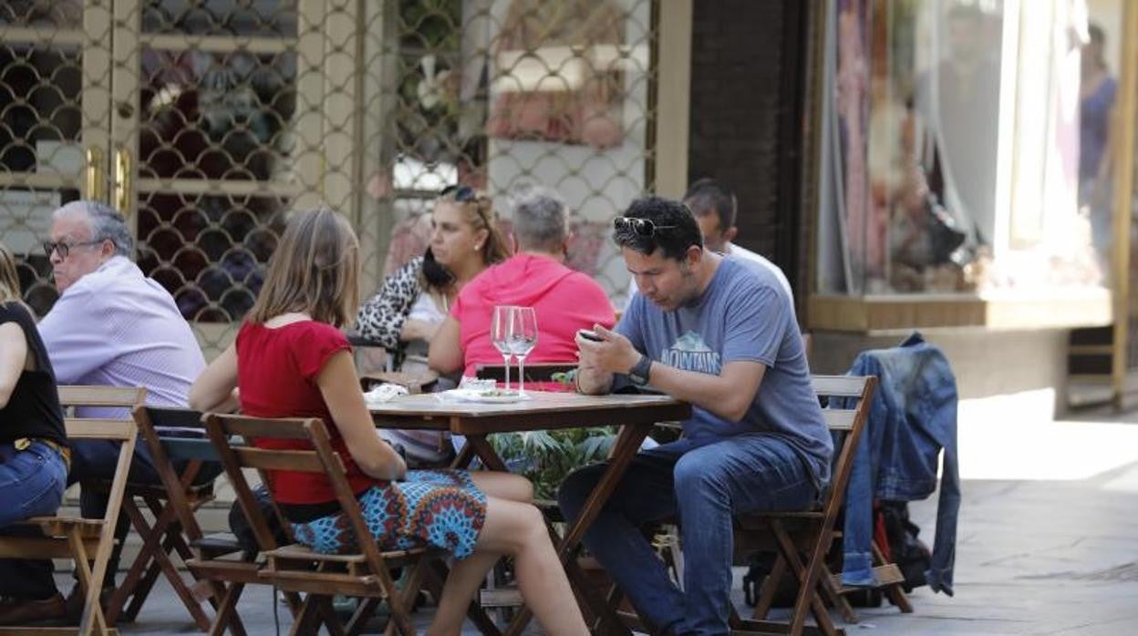 Varias personas en la terraza de un bar de Sevilla