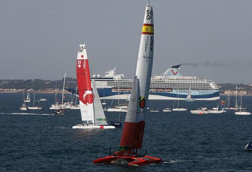 El F50 del equipo español llega a meta en primer lugar con un crucero que hizo escala en Cádiz de fondo.